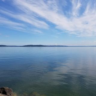 A serene view of a tranquil lake under a clear blue sky with gentle clouds.