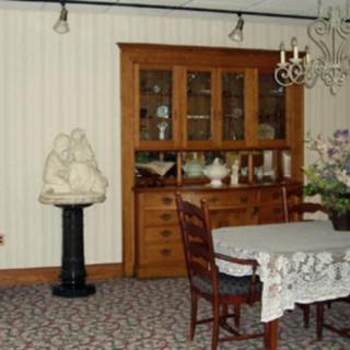 A traditional dining room featuring a wooden cabinet, table, chairs, and a chandelier.