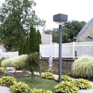 A well-maintained garden with lush greenery and a modern lamp post, situated in a residential neighborhood.