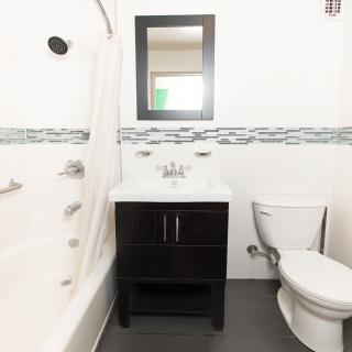 A modern bathroom featuring a bathtub, sink with vanity, toilet, and wall-mounted mirror.