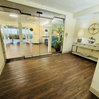 A spacious and inviting lobby featuring modern decor, elegant wooden flooring, and natural light filtering through glass doors.
