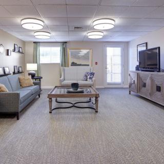 A well-lit living room featuring a comfortable sofa, coffee table, and television setup.