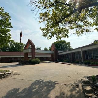 A view of a school building featuring a courtyard and surrounded by trees.
