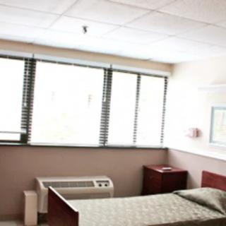 A hospital room with a bed and large windows.