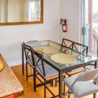 A dining room with a glass table, chairs, and a large mirror on the wall.