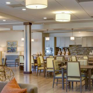 A modern dining area with neatly arranged tables and chairs, featuring soft lighting.