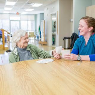 A caregiver and an elderly woman share a joyful moment at a community center.