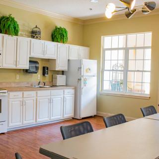 A bright kitchen and dining area with white cabinets, a refrigerator, and a large window.