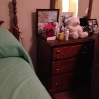 A cozy bedroom scene with a dresser topped with personal items and a teddy bear.