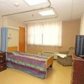A hospital room with a bed, television, and comfortable chair.