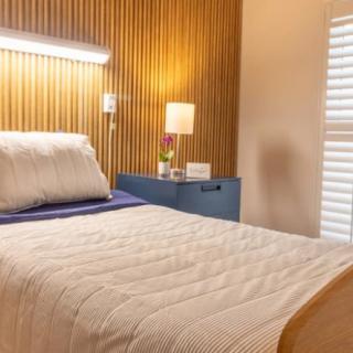 A modern bedroom with a wooden headboard, cozy lighting, and a neatly made bed.
