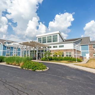 A modern building with a landscaped entrance and a clear blue sky.