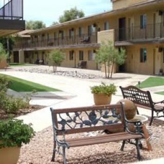 A courtyard view of an apartment complex with benches and landscaped pathways.