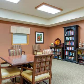 A cozy meeting room featuring a table with chairs, a bookshelf filled with books, and artwork on the wall.