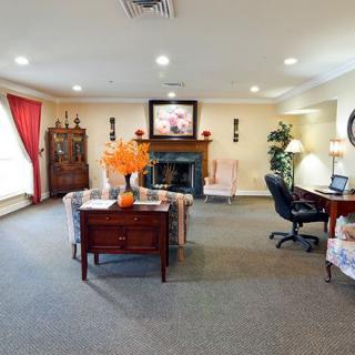 A cozy living room with a combined office area, featuring a fireplace, elegant furniture, and decorative elements.