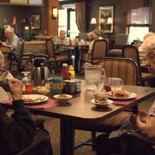Seniors enjoying a meal and conversation in a cozy dining setting.