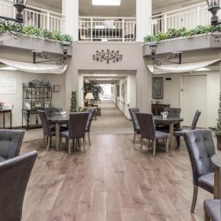 A spacious indoor atrium with tables and chairs arranged in a well-lit area, decorated with plants and elegant decor.