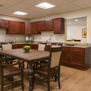 A modern kitchen with wood cabinets and a dining table equipped with chairs.
