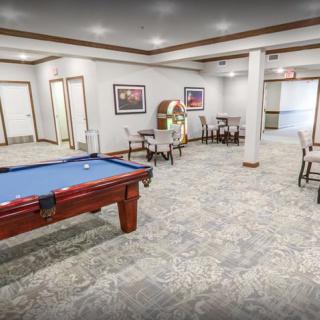 A spacious recreation room featuring a pool table, jukebox, and various seating areas.