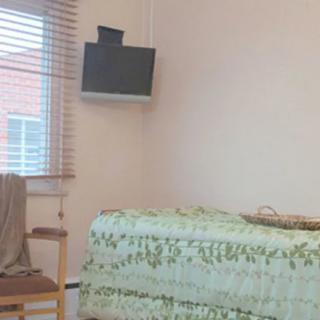 A simple room with a bed, television, and window with blinds.