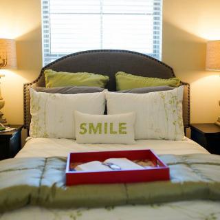A cozy bedroom with a neatly made bed, featuring decorative pillows and bedside lamps.