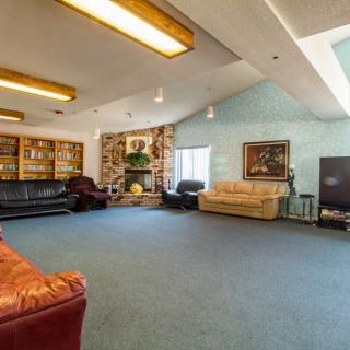 Spacious living room with multiple couches, bookshelves, and large windows.