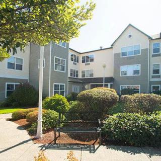 A residential building surrounded by neatly maintained gardens and bushes.