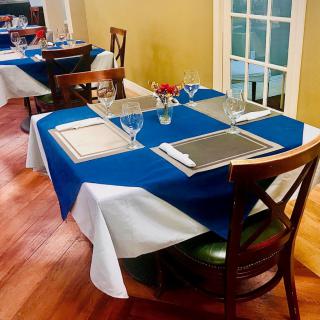 A neatly set dining table in a restaurant with blue and white tablecloths and glassware.