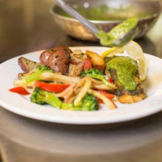 A vibrant plate of sauted vegetables and protein, garnished with fresh herbs and a slice of lime.