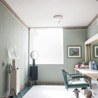 A well-lit hair salon interior featuring a styling chair, large mirror, and salon equipment.