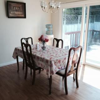 A cozy dining area with a table set for four, adorned with a floral tablecloth and centerpiece, illuminated by a chandelier, and adjacent to large sliding doors.