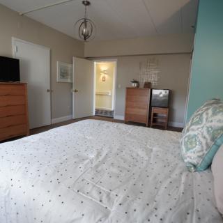 A modern bedroom with a neatly made bed, a TV, and dressers.