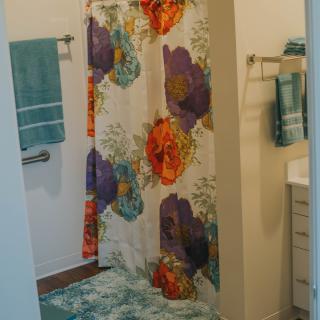 A bathroom with a colorful floral shower curtain and matching towels.