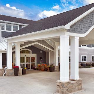 A welcoming entrance to a modern residential building, featuring elegant columns and a well-maintained facade.