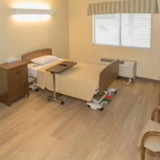 A clean and well-organized hospital room with a single bed and basic furnishings.