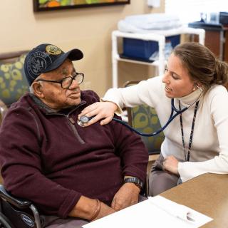 A healthcare professional using a stethoscope to examine a patient in a medical setting.