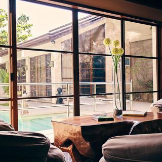 A spacious living room with large windows offering a serene outdoor view and abundant natural light.