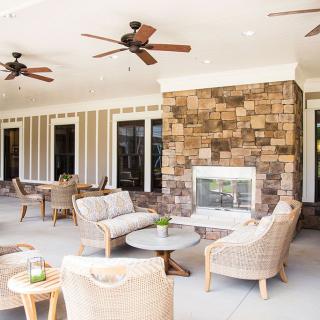 A cozy outdoor patio with comfortable seating and a stone fireplace, perfect for relaxation.