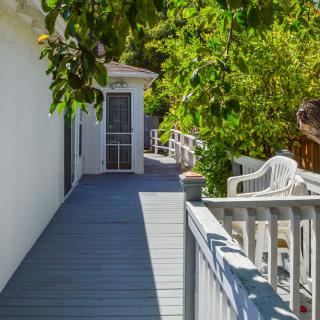A sunlit walkway surrounded by lush greenery and a white fence.