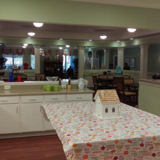 A kitchen area with a decorated table and a gingerbread house centerpiece.