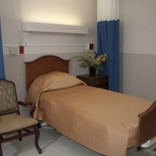 A well-organized hospital room with a bed, chair, and flowers on the side table.