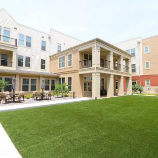 A modern apartment complex with a well-maintained lawn and outdoor seating.