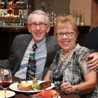 A cheerful couple enjoying a formal dinner with wine at a restaurant.