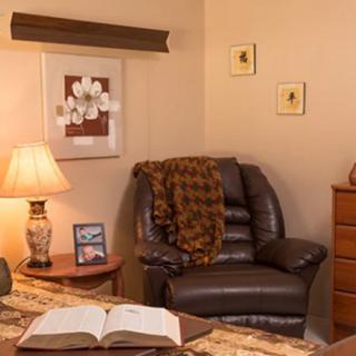 A cozy living room corner with an armchair, lamp, and open book.