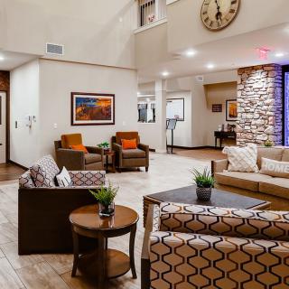 A modern living room with stylish furniture and decor, featuring a large wall clock and framed artwork.