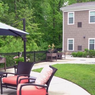 A peaceful backyard patio setup with outdoor seating, umbrella, and lush greenery.