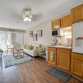 A cozy apartment living room with a kitchenette, featuring modern decor and wood flooring.