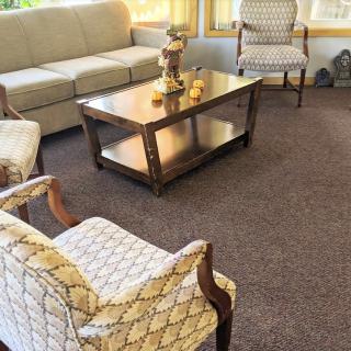 A cozy living room with a sofa, chairs, and a wooden coffee table on a carpet.