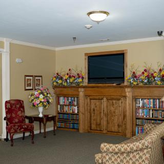 Cozy living room with a mounted television, bookshelves, and floral decor.