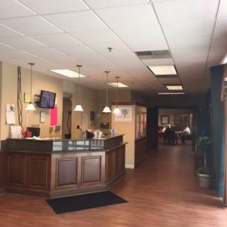 A reception area with a desk and wooden flooring.
